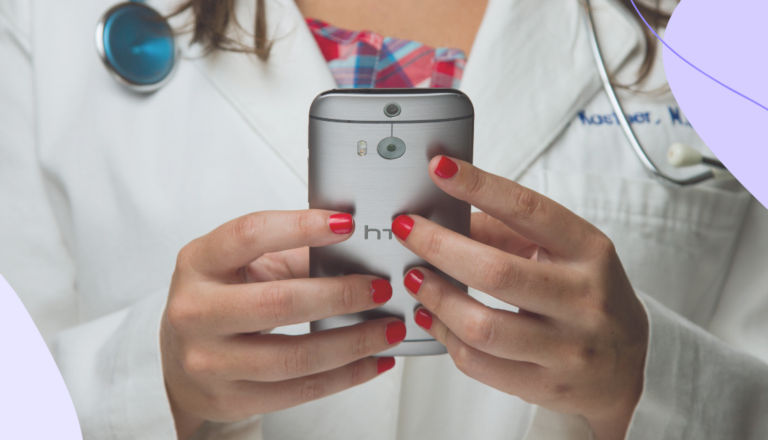 Female doctor holding a mobile phone in her hands with a stethoscope around her neck.