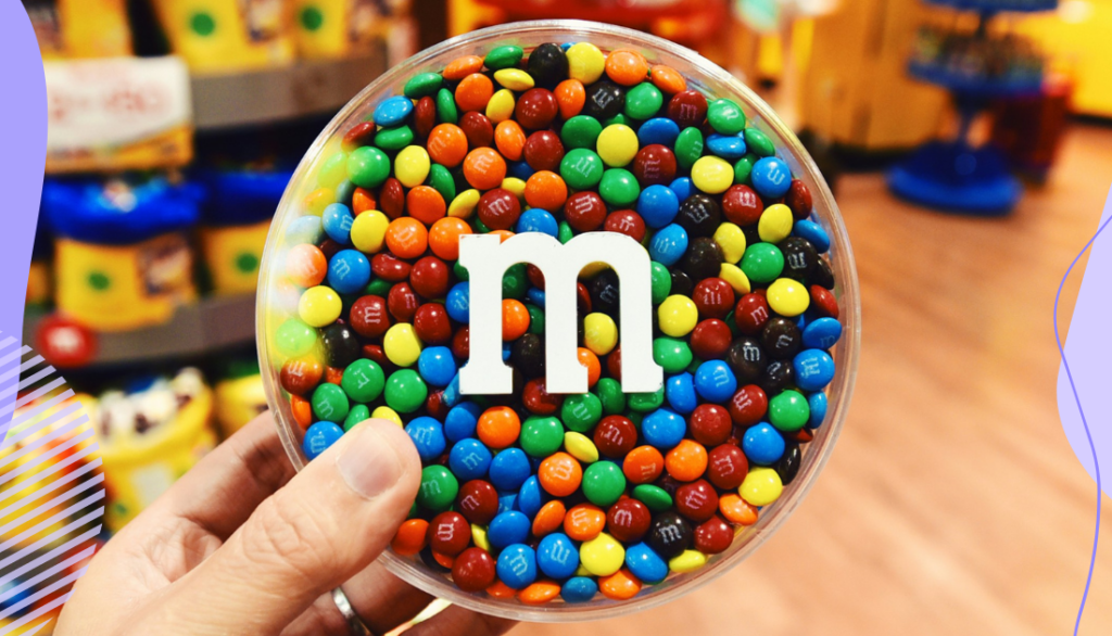 A container of M&M candies held in someone's hand in an M&M store